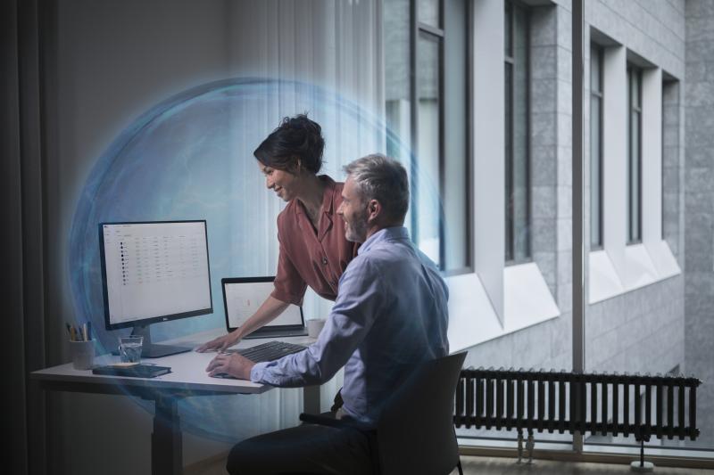 man and woman at standing at a desk watching screen, with conceptual blue cyber protection
